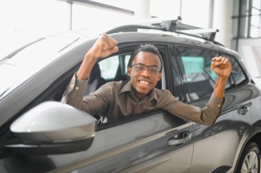 Genç yakışıklı bir adam araba galerisinde araba seçiyor..