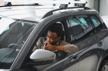 Genç Afrikalı Amerikalı adam araba galerisinde yeni bir araç seçiyor..