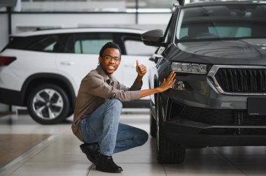 Genç Afrikalı Amerikalı adam araba galerisinde yeni bir araç seçiyor..