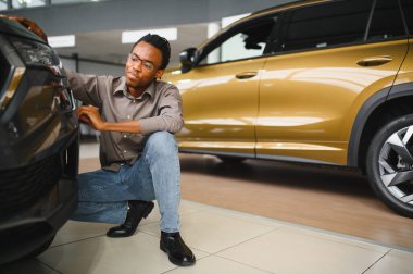 Yerel bayilikte yeni arabasının yanında poz veren mutlu bir Afrikalı adamın portresi..