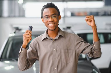 Genç Afrikalı Amerikalı adam araba galerisinde yeni bir araç seçiyor..