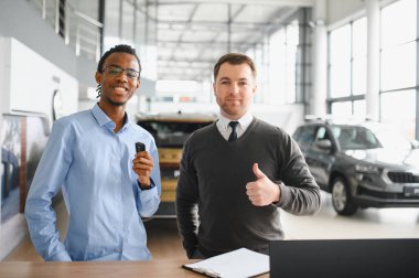 Otomobil salonunda erkek müşteriyle anlaşma yapan bir satıcı. Araba merkezinden yeni araç alan sakallı adam..