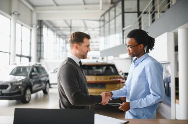 Kafkasyalı satış temsilcisi ve Afrikalı müşteri bayilikte el sıkışırken, satışı kabul ettiler..