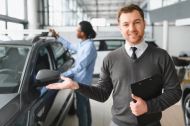 Modern araba satıcısının portresi fotokopi alanı olan bir araba salonunda duruyor..