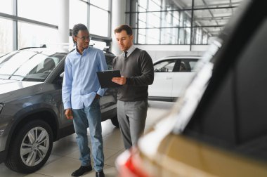 Bir araba galerisinde danışman, müşteriye yeni bir araba seçmesinde yardımcı olur..