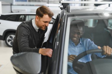 Erkek müşterinin portresi galeride profesyonel araba satıcısıyla konuşuyor. Yeni otomobil seçimi ve satın alma kavramı.