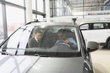 Bir araba galerisinde danışman, müşteriye yeni bir araba seçmesinde yardımcı olur..