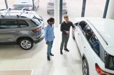 Bir araba galerisinde danışman, müşteriye yeni bir araba seçmesinde yardımcı olur..