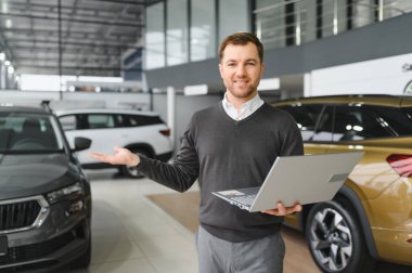 Modern araba satıcısının portresi fotokopi alanı olan bir araba salonunda duruyor..