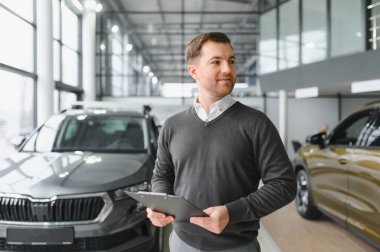 Modern araba satıcısının portresi fotokopi alanı olan bir araba salonunda duruyor..