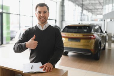 Modern araba satıcısının portresi fotokopi alanı olan bir araba salonunda duruyor..