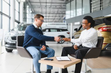 Bir araba galerisinde danışman, müşteriye yeni bir araba seçmesinde yardımcı olur..