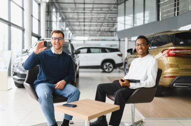 Adamın biri yeni bir arabanın anahtarlarını tutuyor. Arabayı almak için bir satıcıyla sözleşme imzalandı..