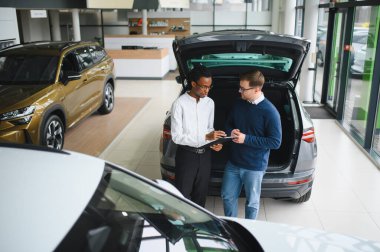Bir araba galerisinde danışman, müşteriye yeni bir araba seçmesinde yardımcı olur..