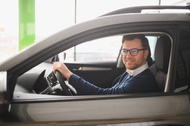 Genç adam yeni bir araç içinde araba Bayilik seçmektir.