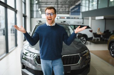 Genç adam yeni bir araç içinde araba Bayilik seçmektir.