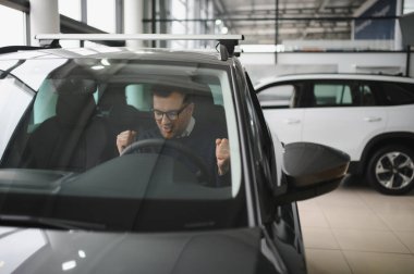 Genç adam yeni bir araç içinde araba Bayilik seçmektir.