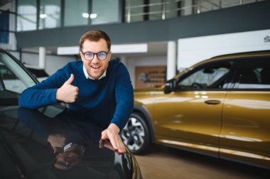 Genç adam yeni bir araç içinde araba Bayilik seçmektir.