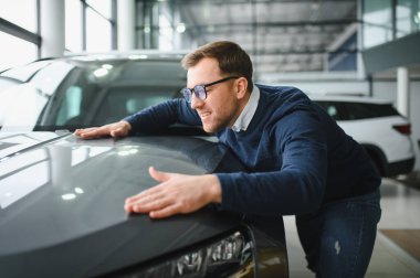 Genç adam yeni bir araç içinde araba Bayilik seçmektir.