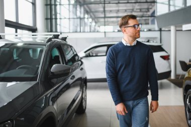 Genç adam yeni bir araç içinde araba Bayilik seçmektir.