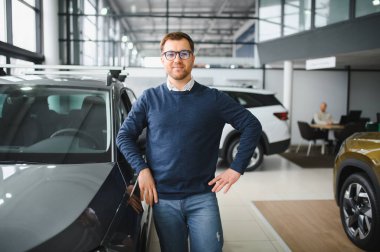 Genç adam yeni bir araç içinde araba Bayilik seçmektir.