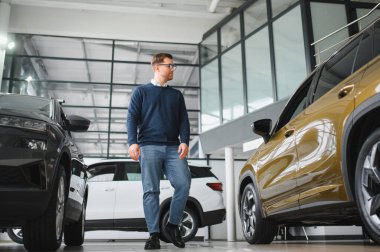 Genç adam yeni bir araç içinde araba Bayilik seçmektir.