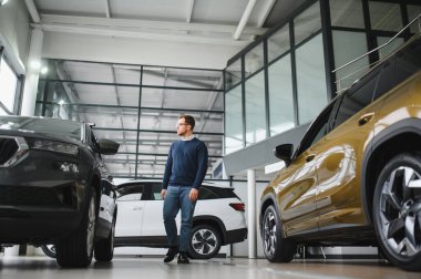 Bugün yeni bir araba aldım. Yerel bayilikte yeni arabasının yanında poz veren mutlu, olgun bir adamın portresi..