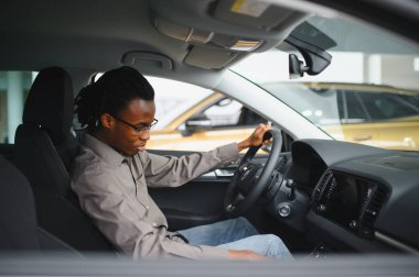 Genç Afrikalı Amerikalı adam araba galerisinde yeni bir araç seçiyor..