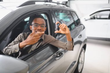 Genç adam yeni bir araç içinde araba Bayilik seçmektir.