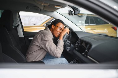 Genç Afrikalı Amerikalı adam araba galerisinde yeni bir araç seçiyor..