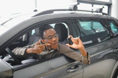 Genç Afrikalı Amerikalı adam araba galerisinde yeni bir araç seçiyor..