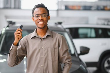 Genç Afrikalı Amerikalı adam araba galerisinde yeni bir araç seçiyor..