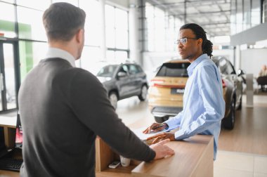 Bir araba galerisinde danışman, müşteriye yeni bir araba seçmesinde yardımcı olur..