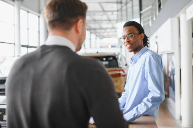 Otomobil salonunda erkek müşteriyle anlaşma yapan bir satıcı. Araba merkezinden yeni araç alan sakallı adam..