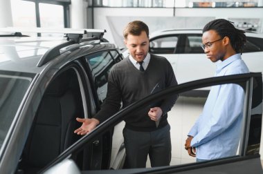 Bir araba galerisinde danışman, müşteriye yeni bir araba seçmesinde yardımcı olur..