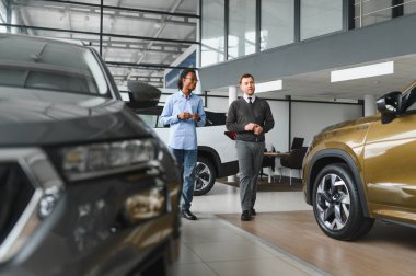 Erkek müşterinin portresi galeride profesyonel araba satıcısıyla konuşuyor. Yeni otomobil seçimi ve satın alma kavramı.