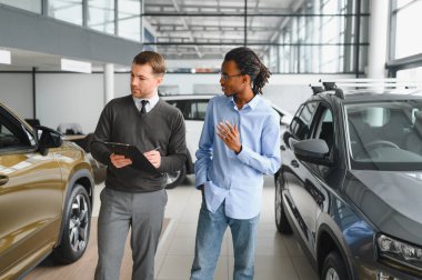 Erkek müşterinin portresi galeride profesyonel araba satıcısıyla konuşuyor. Yeni otomobil seçimi ve satın alma kavramı.