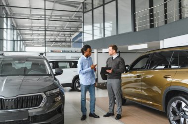 Erkek müşterinin portresi galeride profesyonel araba satıcısıyla konuşuyor. Yeni otomobil seçimi ve satın alma kavramı.