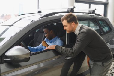 Bir araba galerisinde danışman, müşteriye yeni bir araba seçmesinde yardımcı olur..