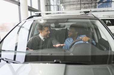 Erkek müşterinin portresi galeride profesyonel araba satıcısıyla konuşuyor. Yeni otomobil seçimi ve satın alma kavramı.