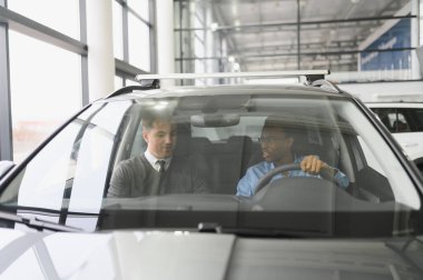 Bir araba galerisinde danışman, müşteriye yeni bir araba seçmesinde yardımcı olur..