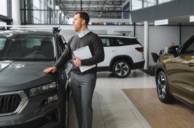 Modern araba satıcısının portresi fotokopi alanı olan bir araba salonunda duruyor..