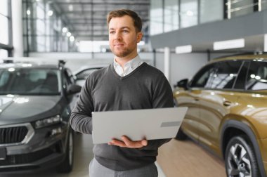 Modern araba satıcısının portresi fotokopi alanı olan bir araba salonunda duruyor..