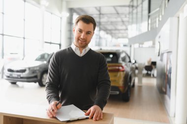 Modern araba satıcısının portresi fotokopi alanı olan bir araba salonunda duruyor..