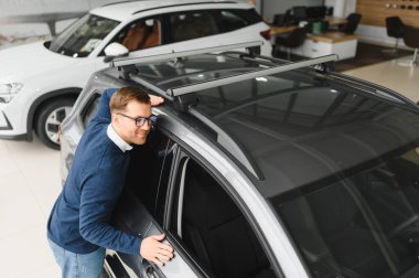 Bugün yeni bir araba aldım. Yerel bayilikte yeni arabasının yanında poz veren mutlu, olgun bir adamın portresi..