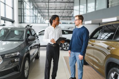 Erkek müşterinin portresi galeride profesyonel araba satıcısıyla konuşuyor. Yeni otomobil seçimi ve satın alma kavramı.