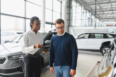 Bir araba galerisinde danışman, müşteriye yeni bir araba seçmesinde yardımcı olur..