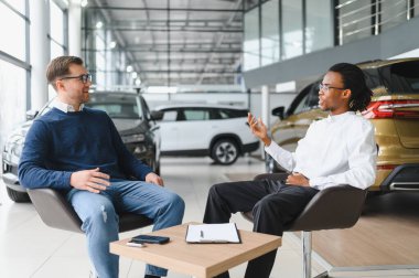 Bir araba galerisinde danışman, müşteriye yeni bir araba seçmesinde yardımcı olur..