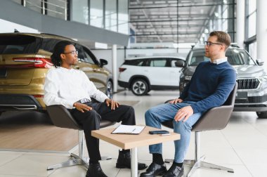 Araba galerisindeki yönetici araba satıcısı. Masada erkek alıcıyla sözleşme imzalıyor..
