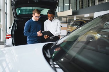 Bir araba galerisinde danışman, müşteriye yeni bir araba seçmesinde yardımcı olur..